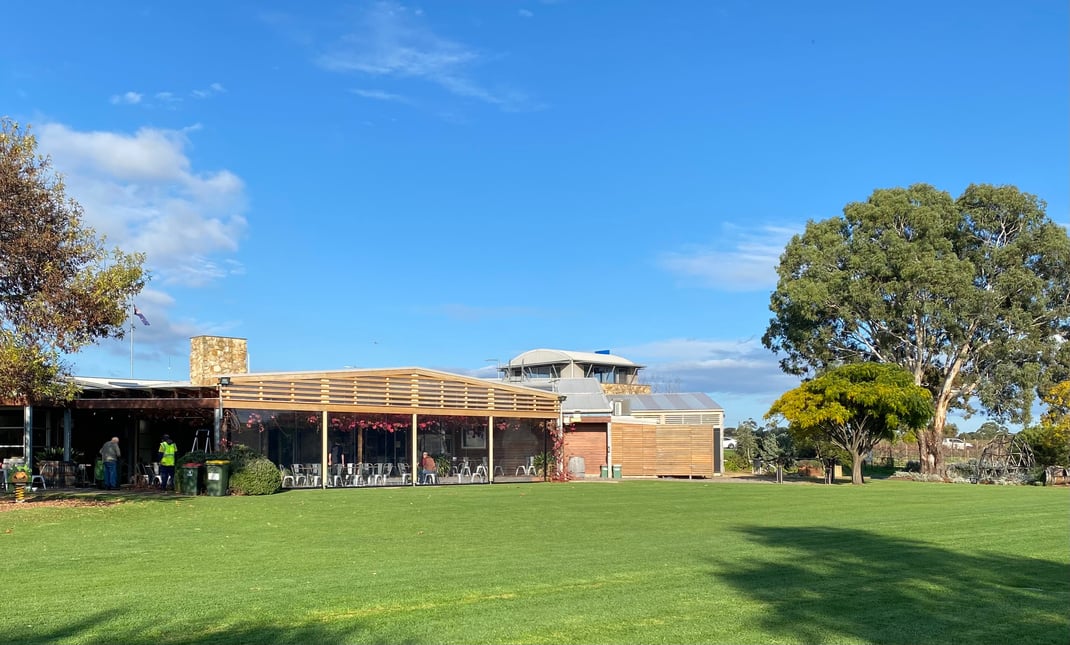 a large grassy area with trees and the McLaren Vale Visitor Information Centre building in the background