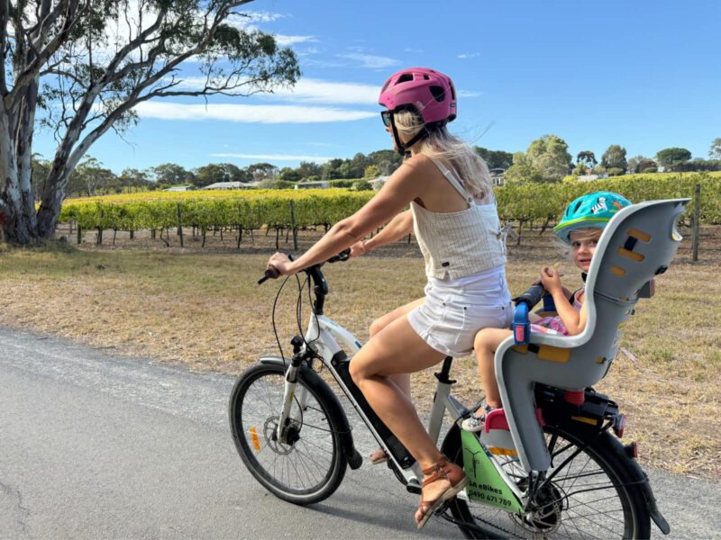 A mother rides an SA eBike, with her young daughter in the childseat behind her