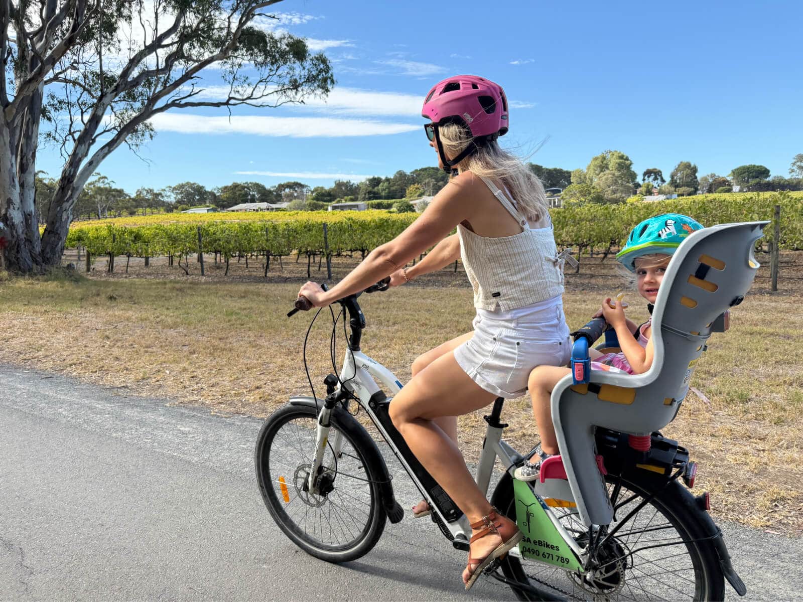 A mother rides an SA eBike, with her young daughter in the childseat behind her