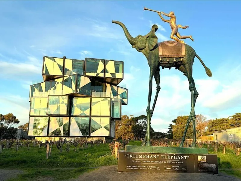 A modern building, D'Arenberg Cube, with a Dali sculpture entitled "Triumphant Elephant" in the foreground