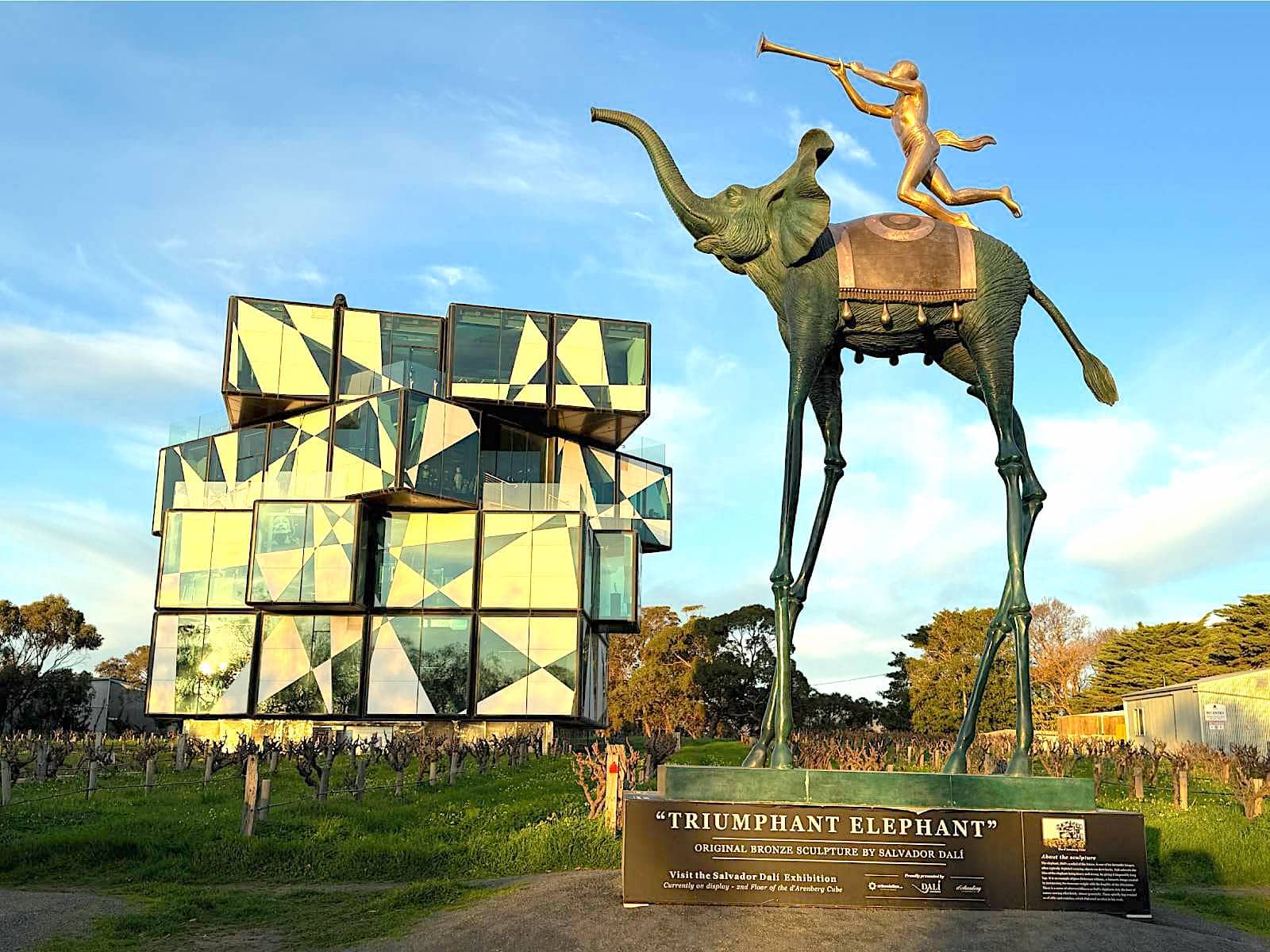 A modern building, D'Arenberg Cube, with a Dali sculpture entitled "Triumphant Elephant" in the foreground
