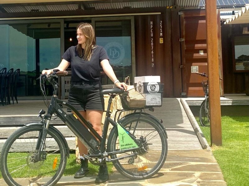 A young woman standing beside her SA eBikes step through bike at the Dowie Doole Cellar Door, McLaren Vale