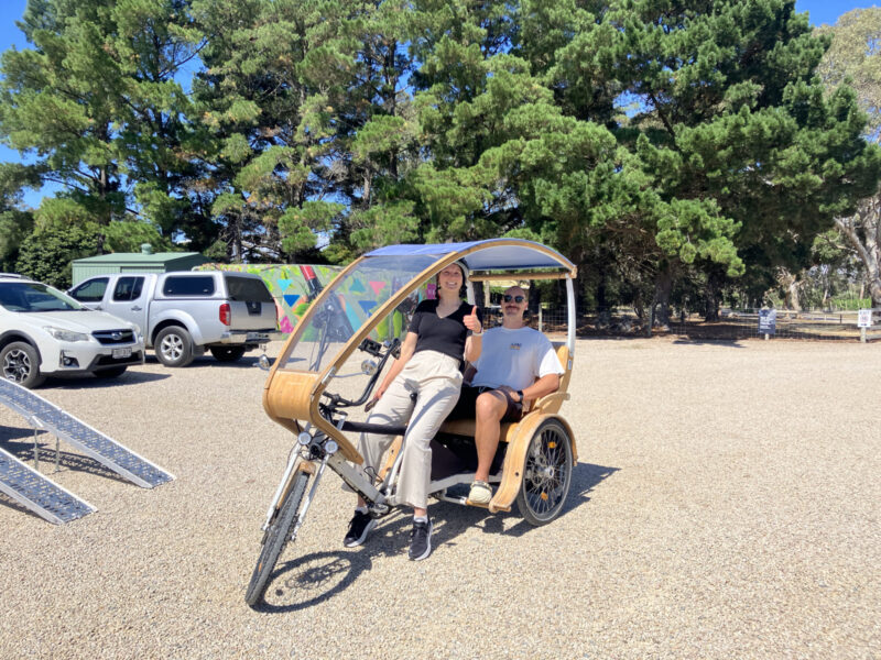 Woman on TukTuk bike seat, with man seated in the bench seat behind the rider at Shirvington Wines