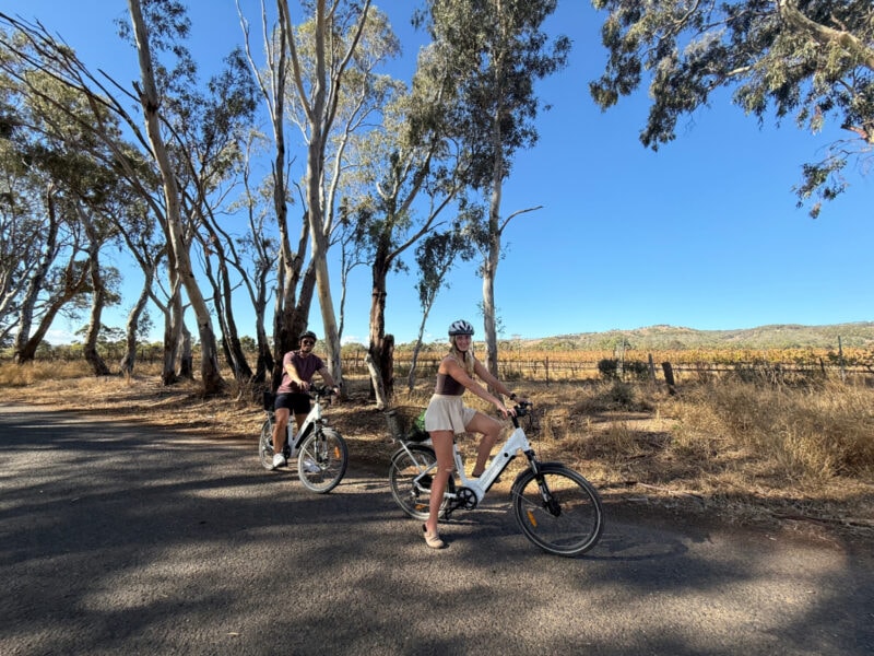 Woman and man riding eBikes on a backroad in McLaren Flat