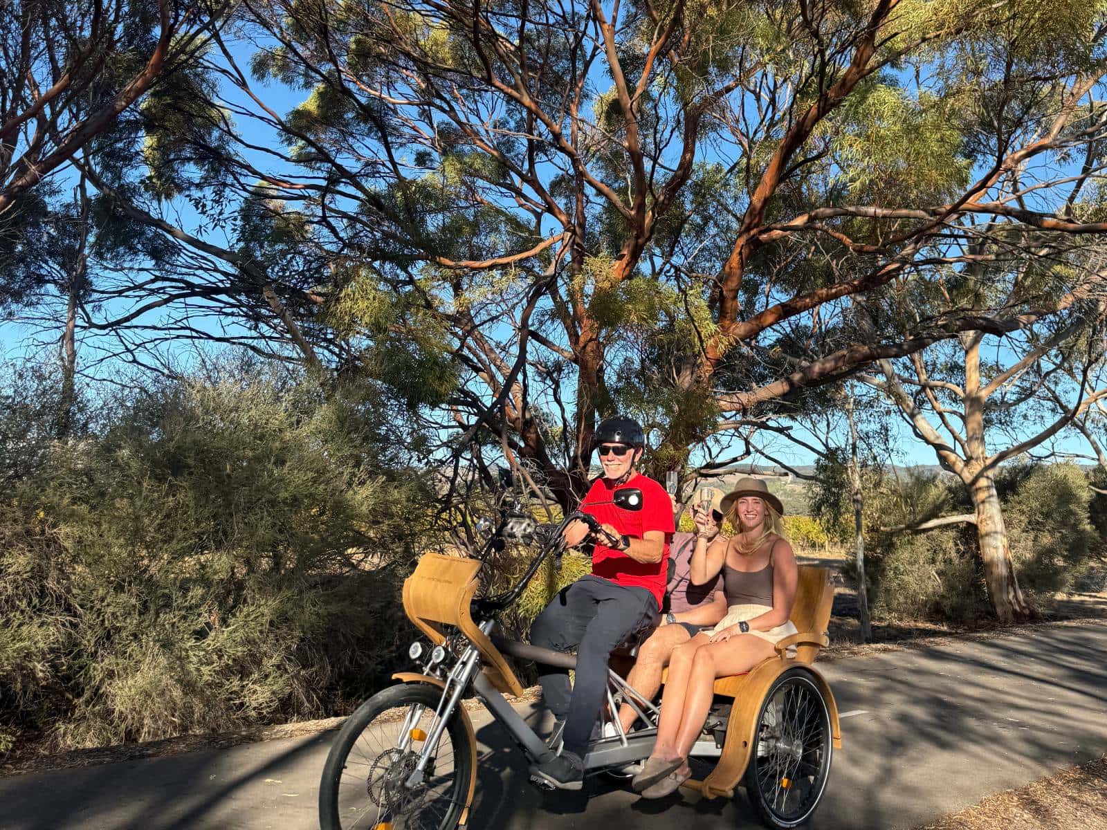 A couple drinking champagne whilst being chauffeured in a TukTuk along the Shiraz Trail, McLaren Vale