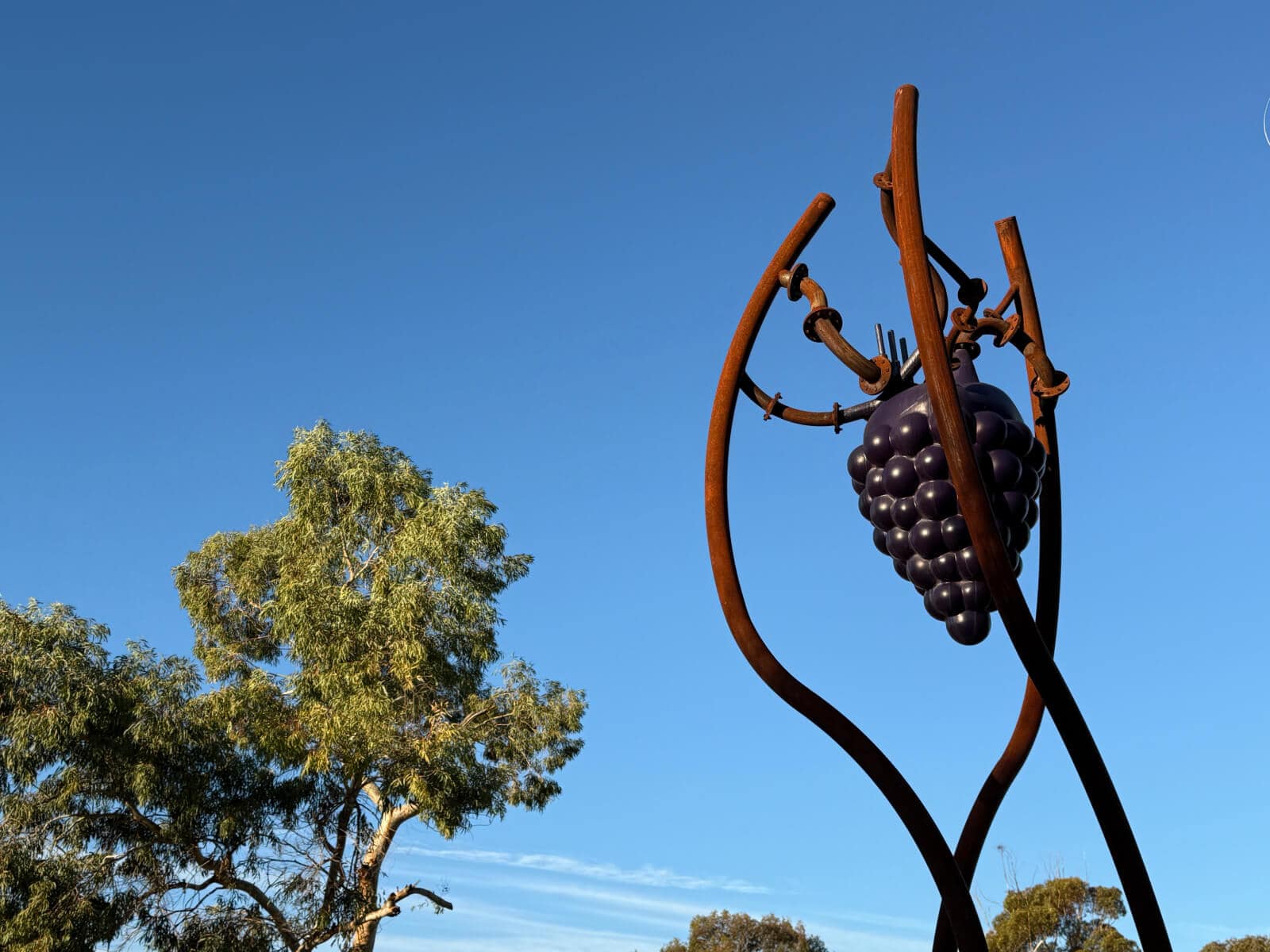 A large sculpture with a bunch of grapes, silhouetted against blue skies