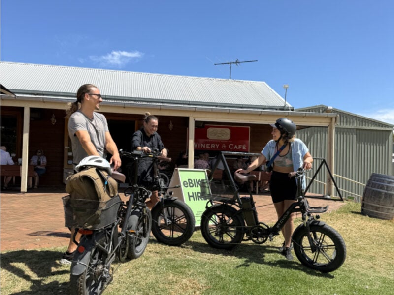 Three young people standing next to eBikes