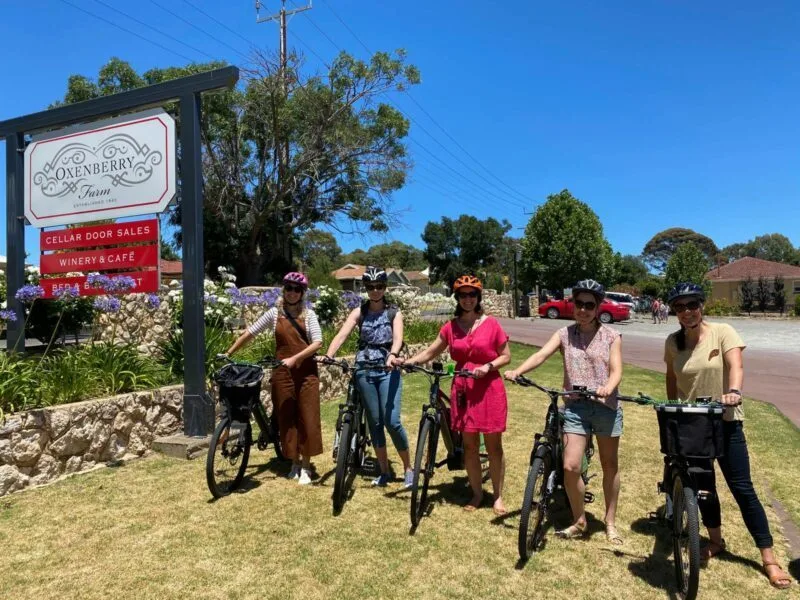 Five women pose with their bikes in front of Oxenberry Farm sign.