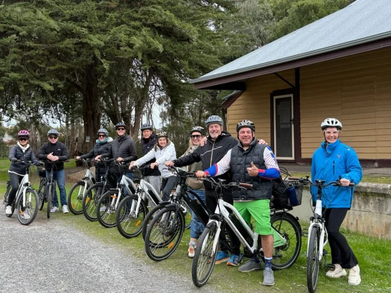 Ten adults standing next to their SA eBikes in front of the former Willunga Railway Station.