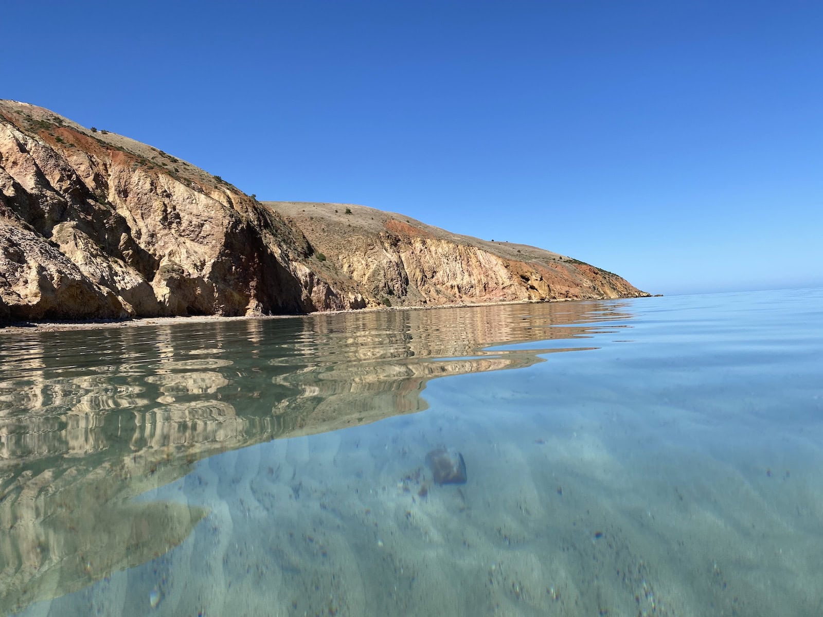 Crystal clear still water at Sellicks Beach with the ochre cliffs in the background