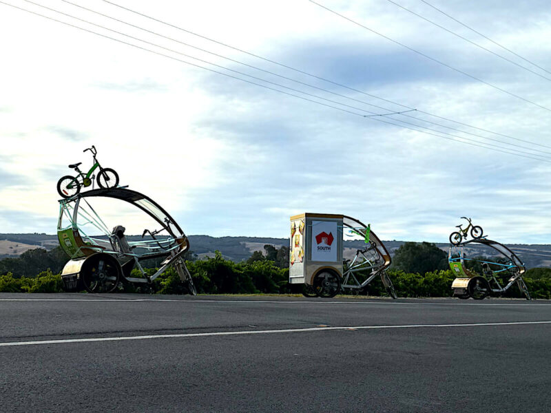A installation for the TDU, of three TukTuks, with childrens bikes attached to canopy along Main Road McLaren Vale