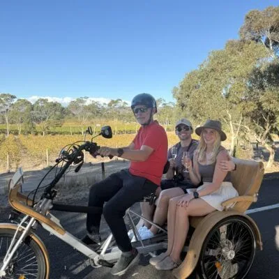 Young smiling couple sit on eTukTuk sipping champagne
