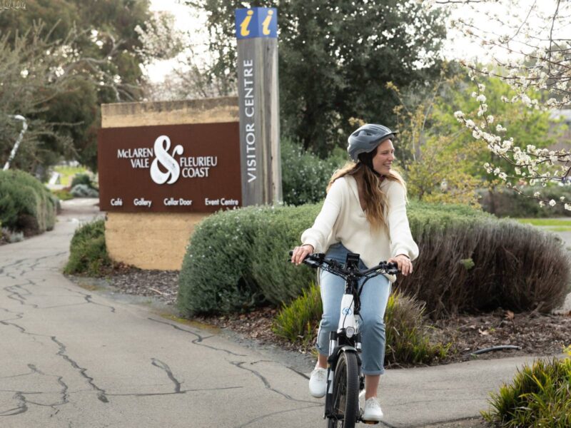 An eBike rider passing the entrance sign to the McLaren Vale VIsitor Information Centre