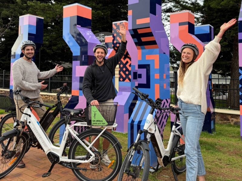 3 people and their eBikes posing in front of purple sculpture in Main St McLaren Vale
