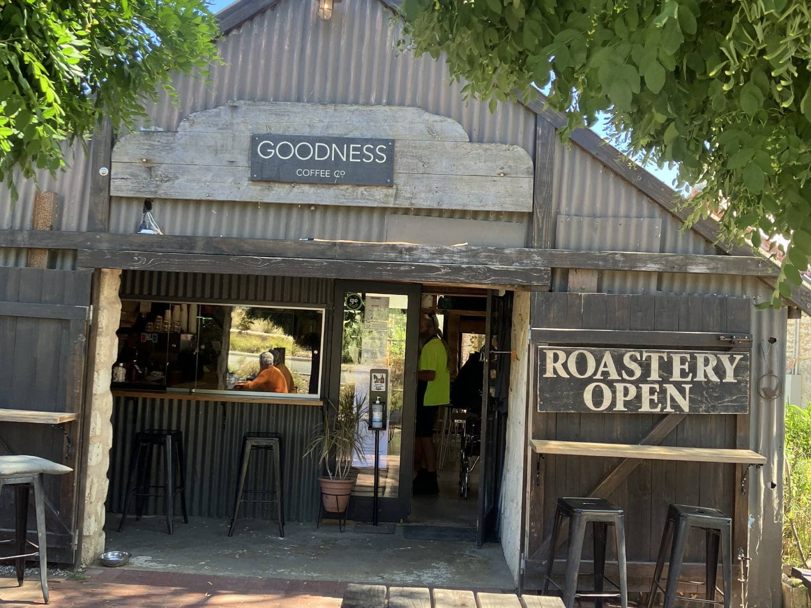 A rustic building with a "Roastery Open" sign displayed at the entrance