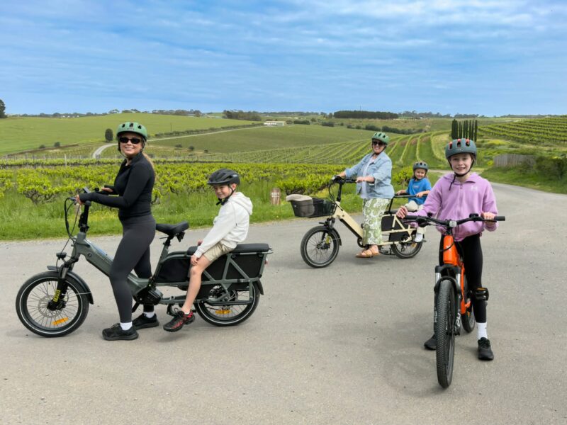 A family group out riding, with children on the back of cargo bikes