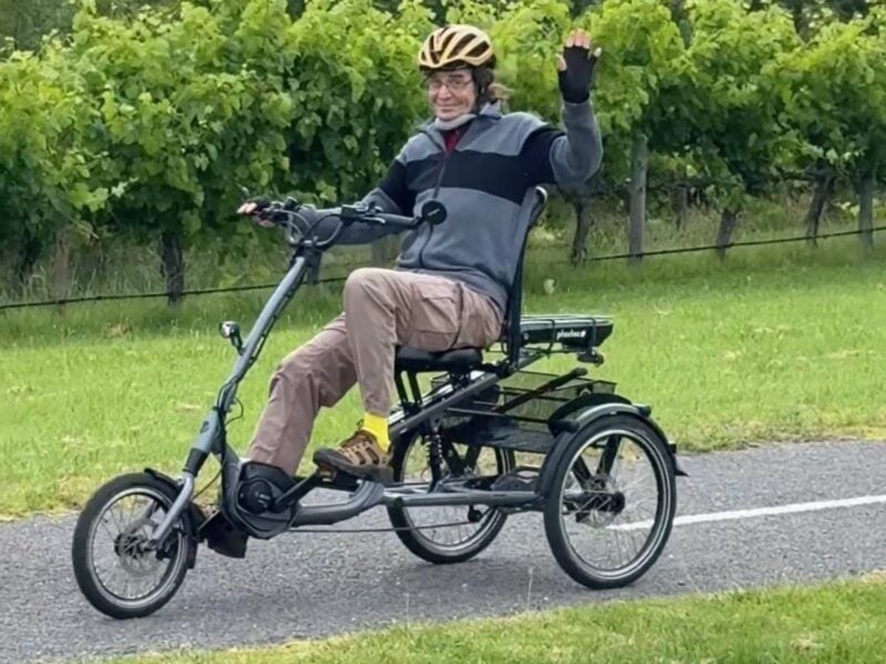 Low centre of gravity trike with rider wearing supportive neck brace