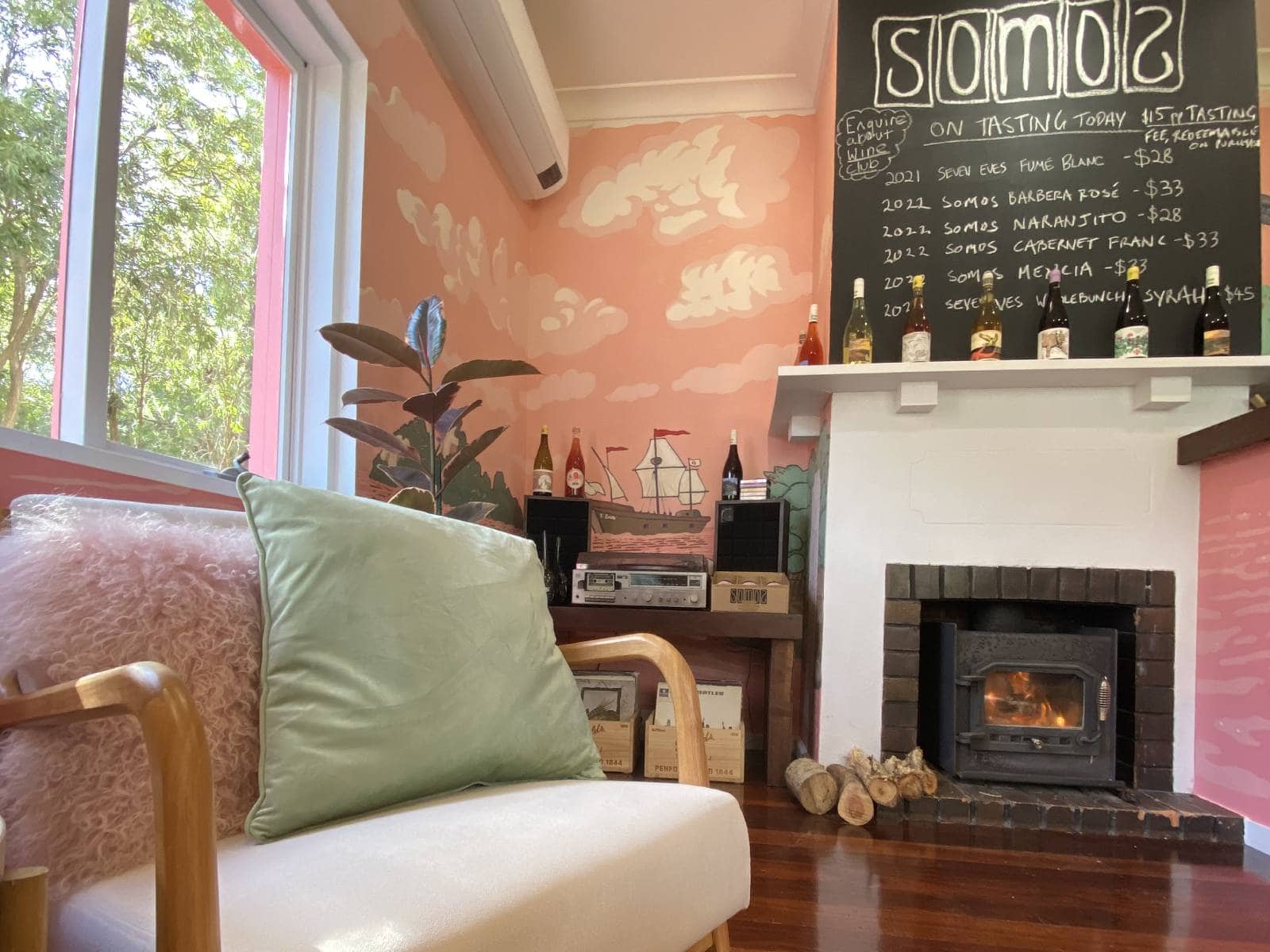 The warm interior of Somos Wines cellar door, with a fireplace and pink walls