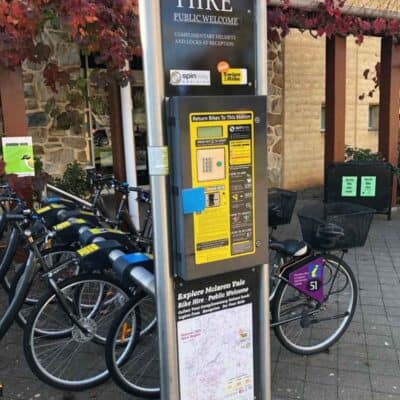 A rack of bikes behind a machine for swiping credit cards to hire the bikes